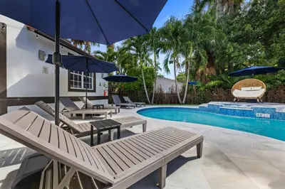 a swimming pool with benches and umbrellas next to a swimming pool at Renovated house w private heated pool grill in Hollywood