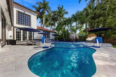 a swimming pool with blue chairs and umbrellas at Renovated house w private heated pool grill in Hollywood
