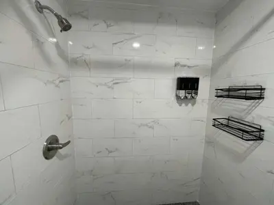 a bathroom with a shower with white marble walls at KING OF MIAMI - 1 mile from Brickell 2BD Apartment! in Miami
