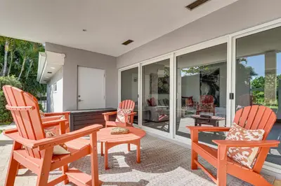 a living room with chairs and a table and windows at Relax in the Sun! Gem 1 Mi to Las Olas Beach in Fort Lauderdale