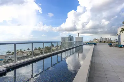 a walkway over a pool on a building with the ocean at Luxury Condo with Serene Balcony View in Hollywood