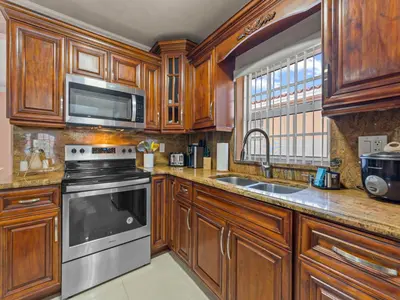 a kitchen with wooden cabinets and a stove and a sink at Tropical Bay House-Near By Brickell, Wynwood and South Beach in Miami