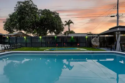 a swimming pool with a sunset in the background at Heated Pool Home - Mini Golf & Soccer & Firepit in Hollywood