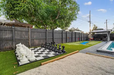 a chess board on a lawn next to a pool at Heated Pool Home - Mini Golf & Soccer & Firepit in Hollywood
