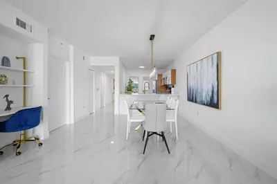 a kitchen and dining room with white walls and white floors at Stylish, classy Bayfront view apt, Walk to beach in Sunny Isles Beach