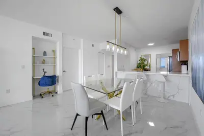 a dining room with a glass table and white chairs at Stylish, classy Bayfront view apt, Walk to beach in Sunny Isles Beach