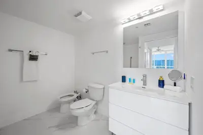 a white bathroom with a toilet and a sink at Stylish, classy Bayfront view apt, Walk to beach in Sunny Isles Beach