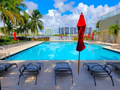 a swimming pool with chairs and a red umbrella at Stylish, classy Bayfront view apt, Walk to beach in Sunny Isles Beach