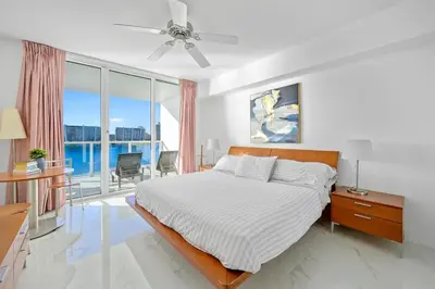 a white bedroom with a bed and a balcony at Stylish, classy Bayfront view apt, Walk to beach in Sunny Isles Beach