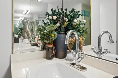 a bathroom sink with a vase with flowers in it at Roney Palace 408 in Miami Beach