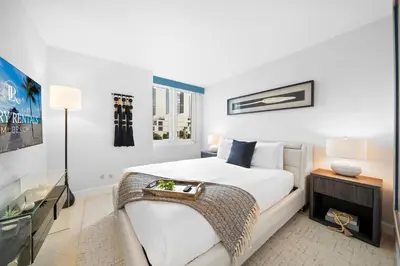 a white bedroom with a bed and a television at Roney Palace 408 in Miami Beach