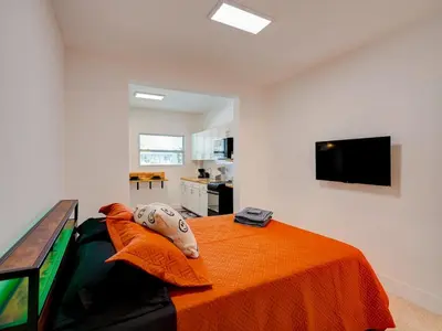 a bedroom with a bed with an orange blanket at Miami Luxury Studio, Close to Wynwood and Beach in Biscayne Park