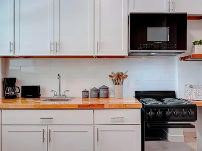 a kitchen with white cabinets and a stove at Miami Luxury Studio, Close to Wynwood and Beach in Biscayne Park