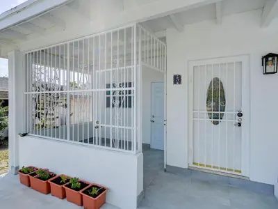a white front door of a house with plants at Miami Luxury Studio, Close to Wynwood and Beach in Biscayne Park