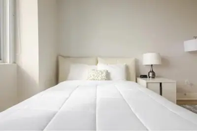 a large white bed in a white bedroom with a lamp at Beachwalk Resort in Hallandale Beach