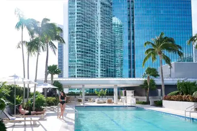 a woman standing next to a swimming pool in a hotel at AKA Hotel Stunning Views w- Free parking in Miami