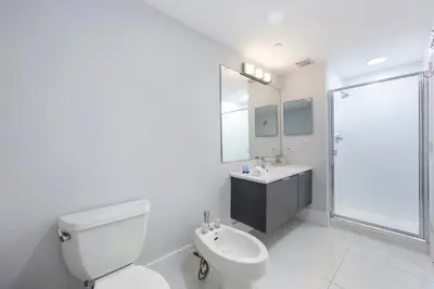 a white bathroom with a toilet and a sink at Golden Bay 702 in Sunny Isles Beach