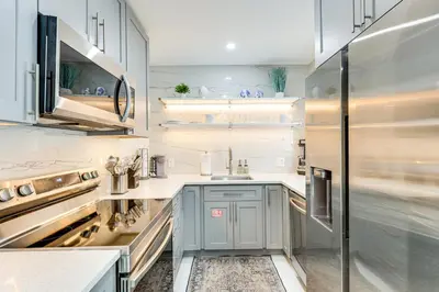 a kitchen with white cabinets and a sink at 1 Mi to Las Olas Eats! Modern Apt with Shared Patio in Fort Lauderdale