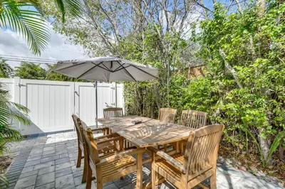 a wooden table with chairs and an umbrella at 1 Mi to Las Olas Eats! Modern Apt with Shared Patio in Fort Lauderdale