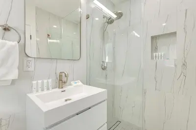 a white bathroom with a sink and a shower at 1 Mi to Las Olas Eats! Modern Apt with Shared Patio in Fort Lauderdale
