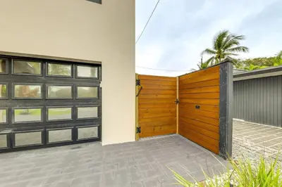 a house with a wooden garage door and a palm tree at Home in Heart of Wilton Drive, 4 Mi to Beach in Fort Lauderdale