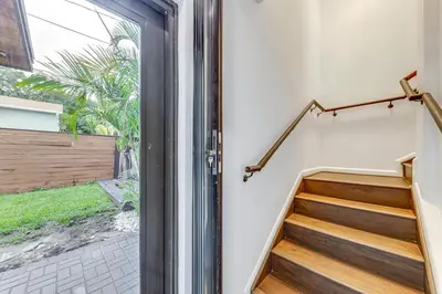 a glass door leading to a staircase with wooden steps at Home in Heart of Wilton Drive, 4 Mi to Beach in Fort Lauderdale