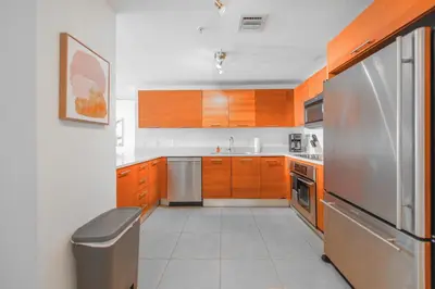 a kitchen with wooden cabinets and a stainless steel refrigerator at Contemporary Midtown Condo - Pool & Free Parking in Miami