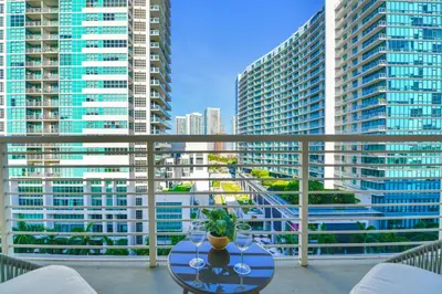 a table on a balcony with a view of tall buildings at Contemporary Midtown Condo - Pool & Free Parking in Miami