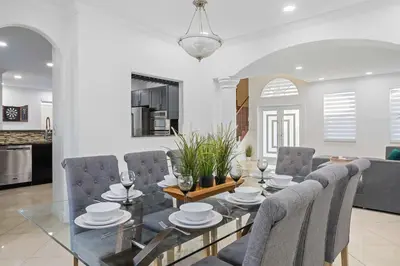 a dining room and living room with a glass table and chairs at Luxury 5BR Villa Private Pool I Jacuzzi I BBQ I Piano I Near Miami Airport in Kendale Lakes