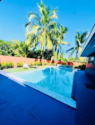 a swimming pool with palm trees in the background at Modern Boho 3BR Duplex Escape with Pool & King Bed Near Beach in Fort Lauderdale