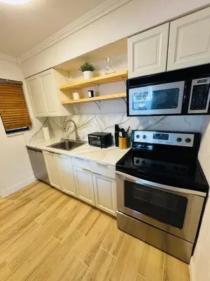 a kitchen with white cabinets and a stove and a sink at Modern Boho 3BR Duplex Escape with Pool & King Bed Near Beach in Fort Lauderdale