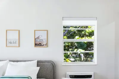 a white bedroom with a window and a couch at The Lemon Branch Hotel in Miami Beach
