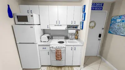 a kitchen with white cabinets and a stove and a microwave at Ocean Front Studio - Miami Beach in Miami Beach