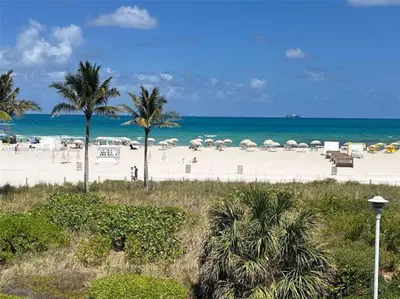a beach with umbrellas and people on the beach at Ocean Front Studio - Miami Beach in Miami Beach