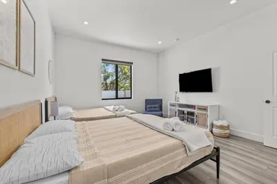 a bedroom with two beds and a flat screen tv at Oasis Yard -Pool-Jets-Game Room-BBQ-Relaxing in Carver Ranches