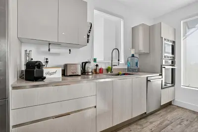 a kitchen with white cabinets and stainless steel appliances at Shoreline Villa by Rove - Rooftop & Beach Access in Hollywood