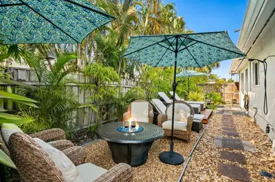 a patio with chairs and a table with two umbrellas at 2 bed, steps from Wilton Drive, BBQ, fire pit in Fort Lauderdale