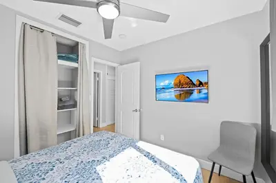 a white bedroom with a bed and a chair at 2 bed, steps from Wilton Drive, BBQ, fire pit in Fort Lauderdale