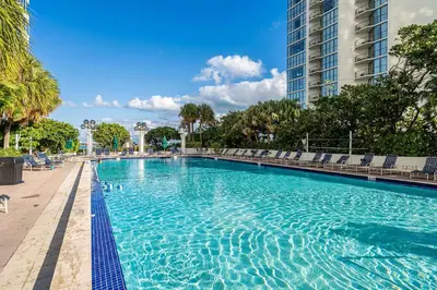 a large swimming pool with chairs and a tall building at Seaview Work Haven Condo for 6 in Miami