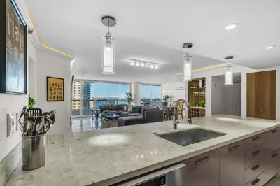 a kitchen with a sink and a living room at Seaview Work Haven Condo for 6 in Miami