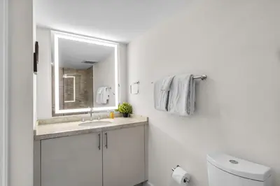 a white bathroom with a sink and a mirror at Seaview Work Haven Condo for 6 in Miami