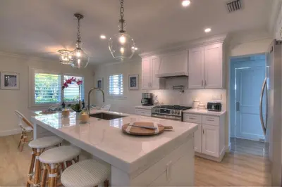a kitchen with white cabinets and a large kitchen island at Beach Oasis Heated Pool, Gazebo, Hot Tub in Fort Lauderdale