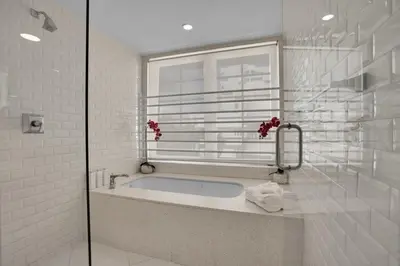 a white bathroom with a tub and a window at Peaceful 2BR Condo with Ocean Views on Ocean Drive South Beach in Miami Beach
