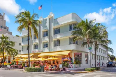a white building with palm trees in front of it at Peaceful 2BR Condo with Ocean Views on Ocean Drive South Beach in Miami Beach