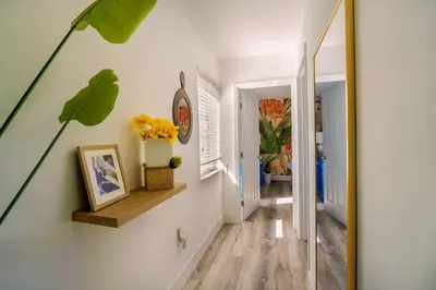 a hallway with white walls and a staircase with flowers on a shelf at Suite Mar - Unit B in Miami