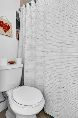 a white bathroom with a toilet and a shower curtain at Buena Vista vacation home with privacy and close to everything in Miami