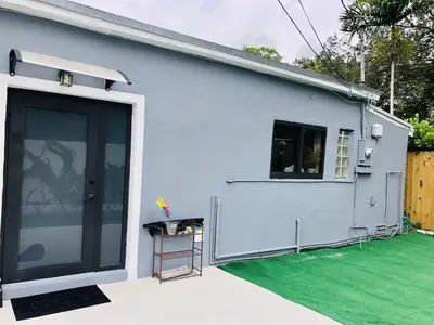 a white house with a door and a green lawn at Buena Vista vacation home with privacy and close to everything in Miami
