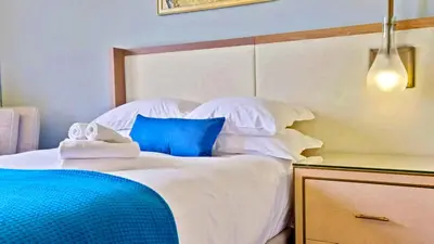 a bed with white sheets and blue pillows on it at Modern Miami Suite Near the Beach in Miami