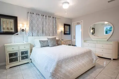 a bedroom with a white bed and a mirror at Wilton Manors Twin Oasis | 2 Heated Pools, For 12 in Fort Lauderdale