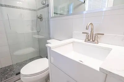 a white bathroom with a sink and a toilet at Wilton Manors Twin Oasis | 2 Heated Pools, For 12 in Fort Lauderdale
